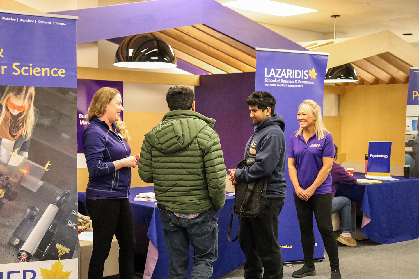 Students speaking with volunteers at a Lazaridis school table