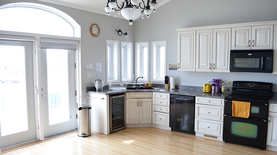 A kitchen with a oven, dishwasher, microwave, fridge, etc. next to a set of french doors.