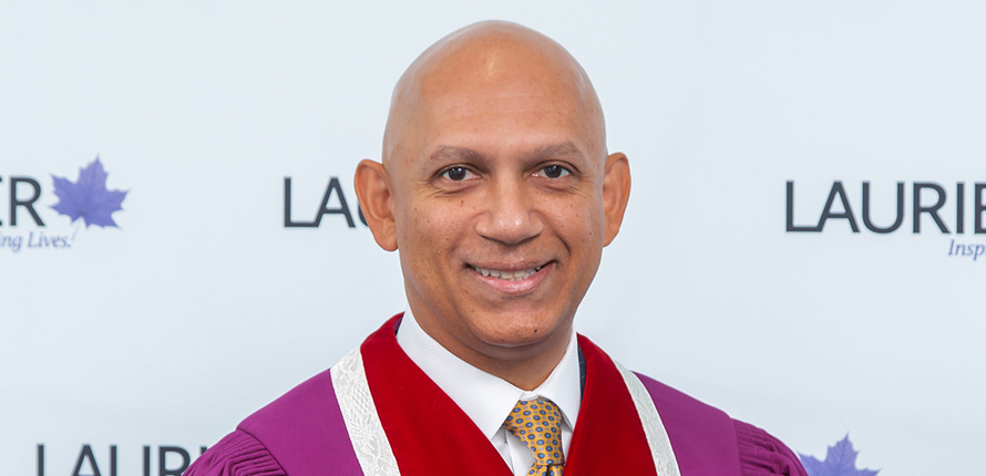 Chancellor Nadir Patel in regalia with Laurier logo in the background