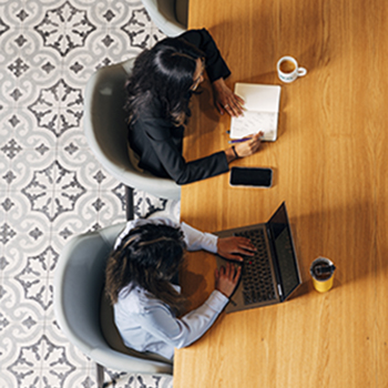 Two students sitting at a desk writing notes