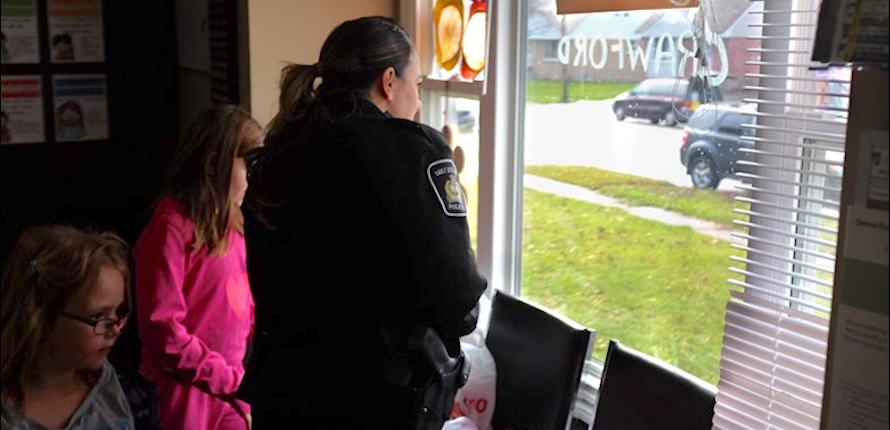 Police officer looking out the window of a community centre with two children