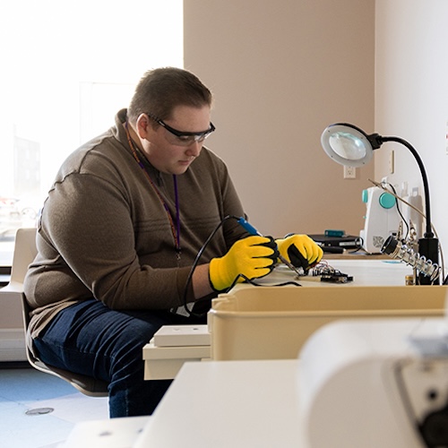 Student soldering at a desk