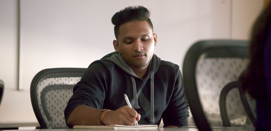 Student writing at a desk