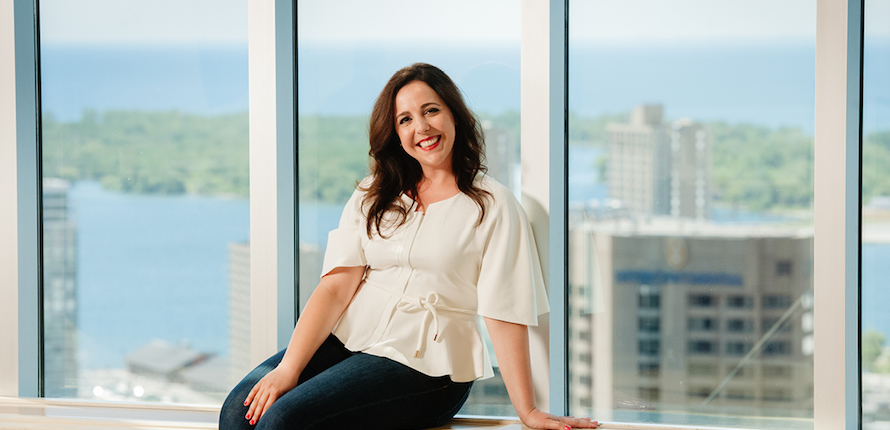 Student sitting on windowsill with skyscrapers in the background