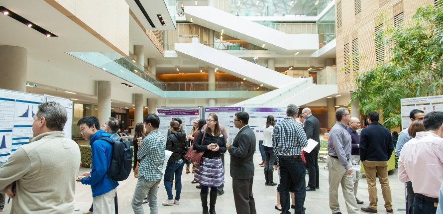 a crowd of people examine research posters in Lazaridis Hall