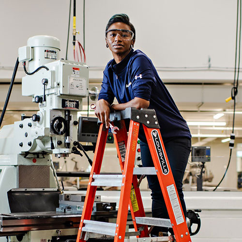 Woman standing on a ladder in a mechanic shop