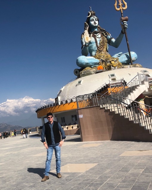 Christopher Wilvert standing at a statue of Lord Shiva.