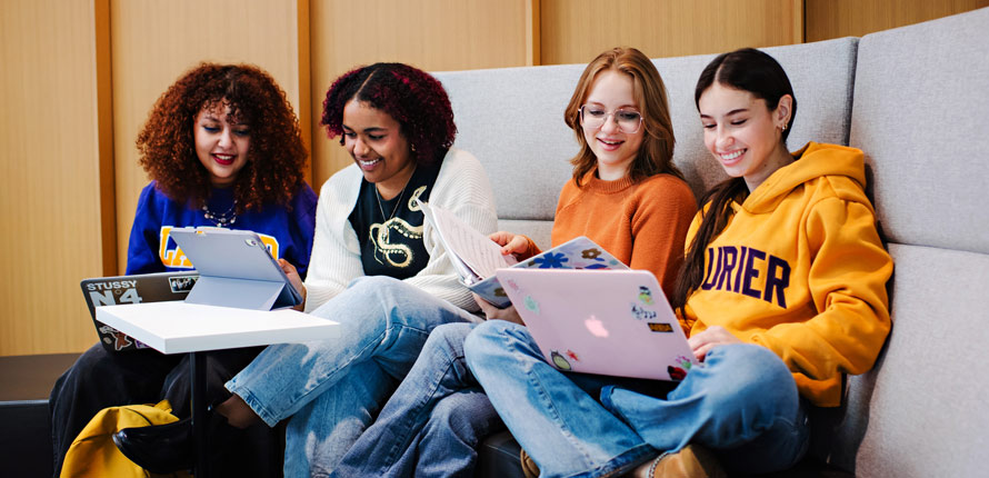 four female students sitting and looking at their laptops