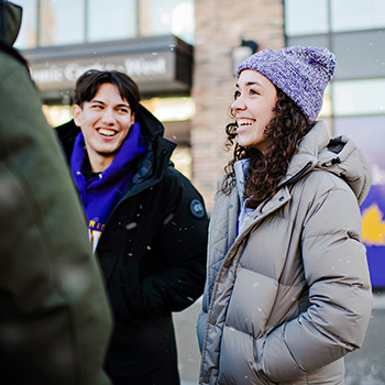 two students smiling and standing outside of Brantford building in winter
