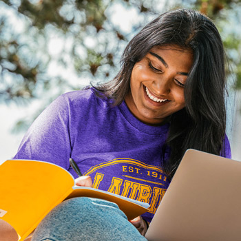 female student smiling taking notes