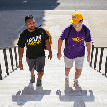 two male students walking upstairs wearing Laurier athletic gear