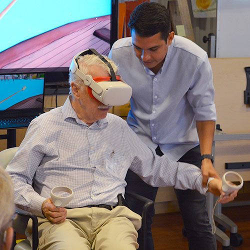 John Munoz assisting a senior with VR exergame
