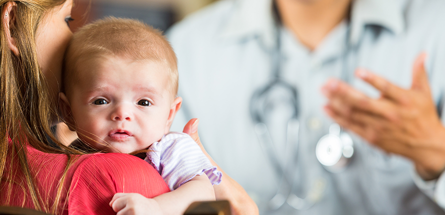 Mother holding baby talking to doctor