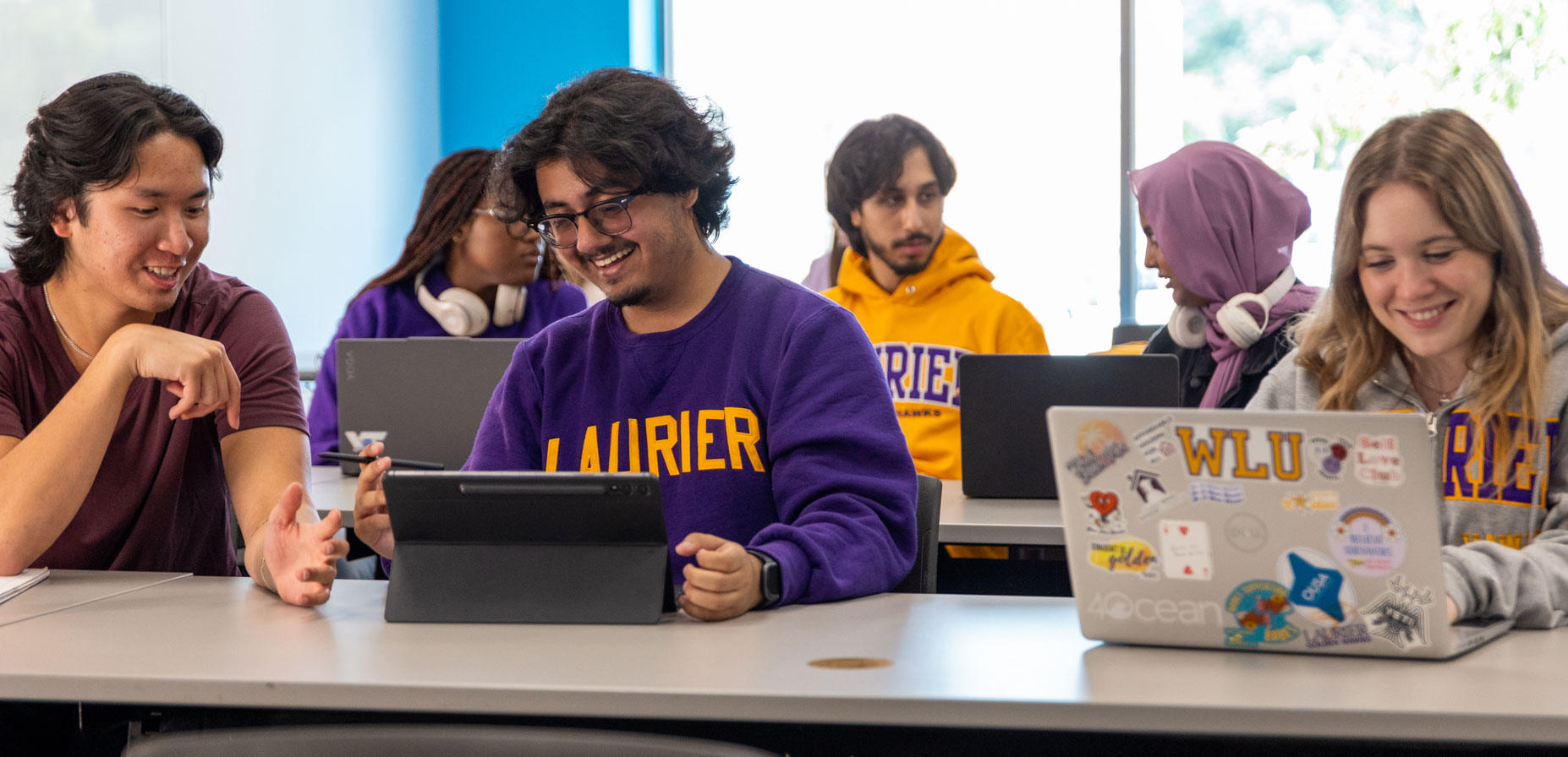 students work together on laptops on campus