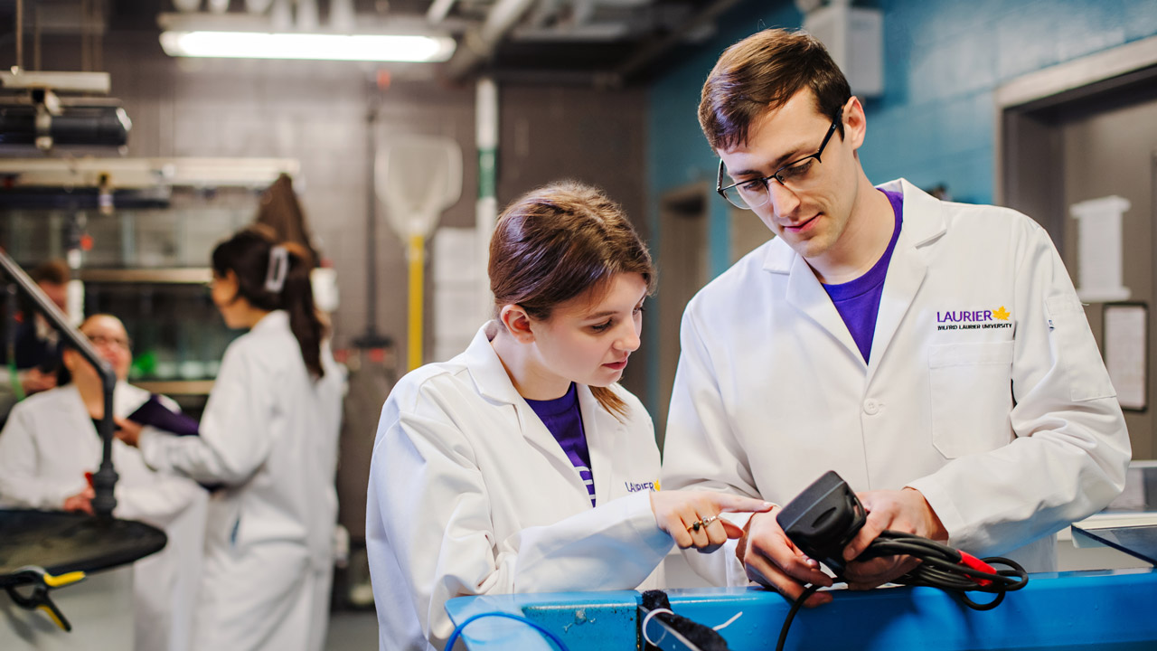 female and male student in lab coats